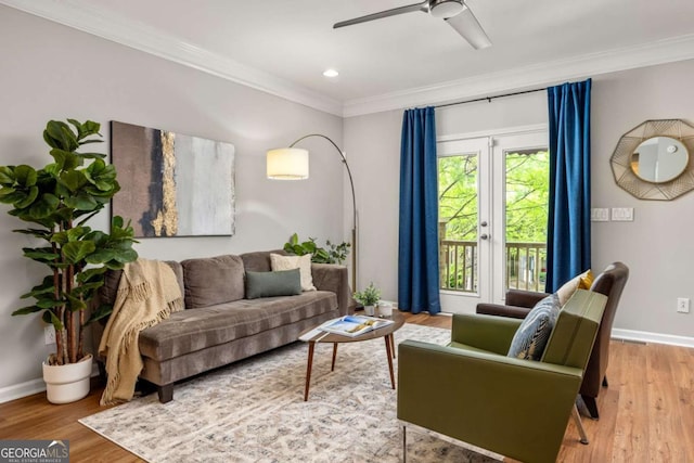 living area featuring baseboards, ornamental molding, a ceiling fan, and wood finished floors