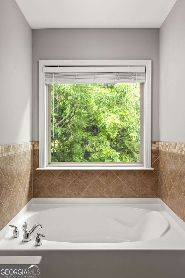 full bath with a garden tub, wainscoting, and tile walls