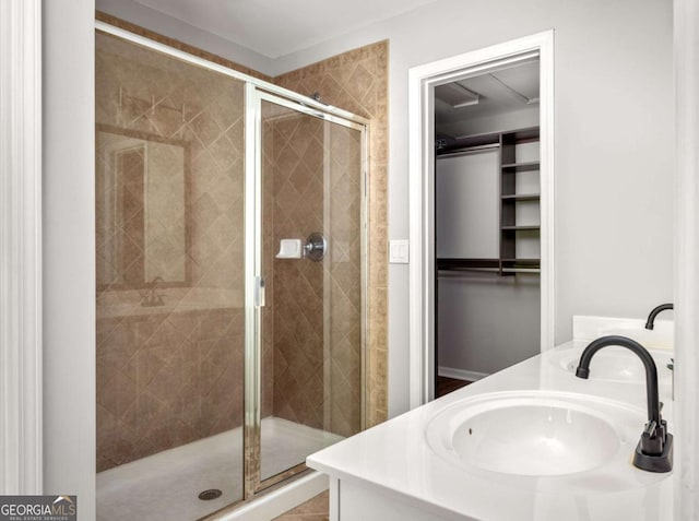 bathroom with a sink, a walk in closet, a stall shower, and double vanity