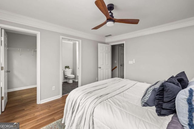 bedroom with visible vents, ornamental molding, a closet, wood finished floors, and a spacious closet