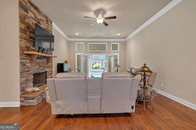 living area featuring baseboards, ceiling fan, a fireplace, and wood finished floors