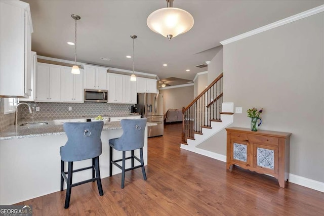 kitchen featuring crown molding, a sink, light stone countertops, and stainless steel appliances