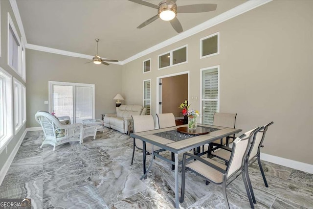 dining area with crown molding, ceiling fan, baseboards, and a high ceiling