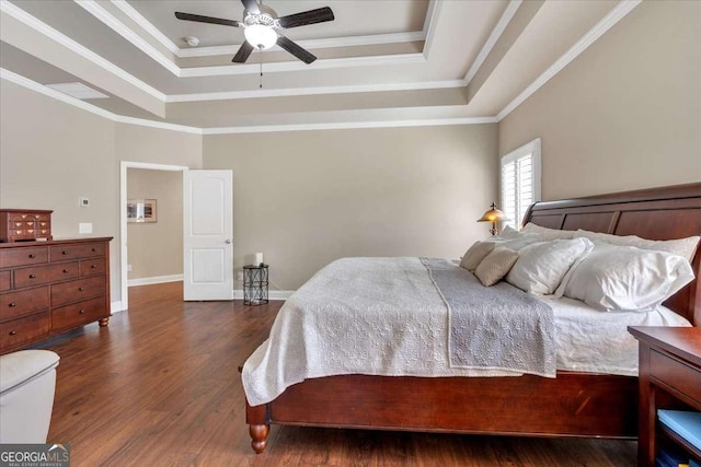 bedroom with baseboards, ornamental molding, a tray ceiling, and wood finished floors