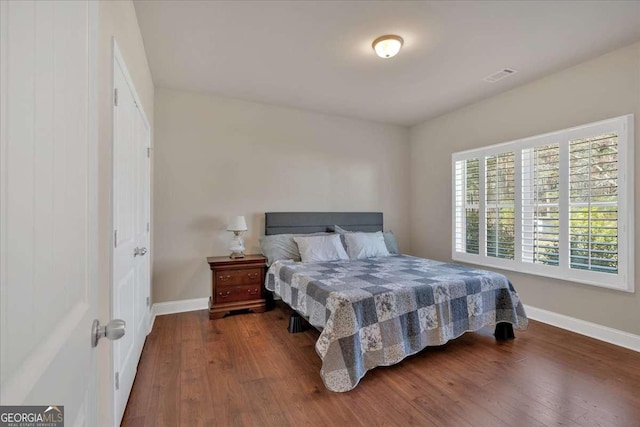 bedroom with baseboards, dark wood finished floors, and visible vents