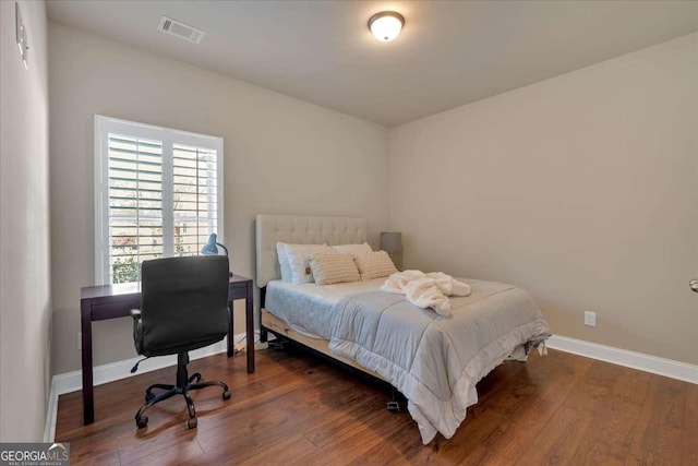 bedroom with visible vents, baseboards, and wood finished floors
