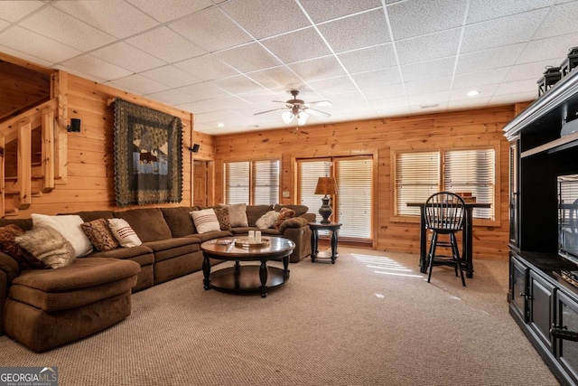 433 Spruce Cir, Mineral Bluff, GA 30559 - carpeted living room featuring wood walls, ceiling fan, a drop ceiling, and a healthy amount of sunlight