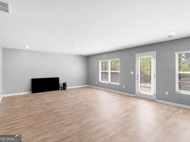 unfurnished living room featuring baseboards, visible vents, plenty of natural light, and light wood-style floors