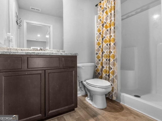 bathroom featuring vanity, toilet, curtained shower, wood finished floors, and visible vents