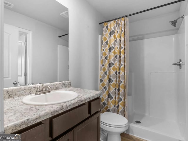 bathroom featuring toilet, a shower with curtain, visible vents, and vanity