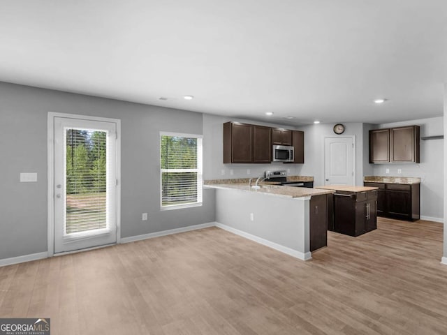 kitchen with dark brown cabinets, baseboards, light wood-type flooring, light countertops, and appliances with stainless steel finishes