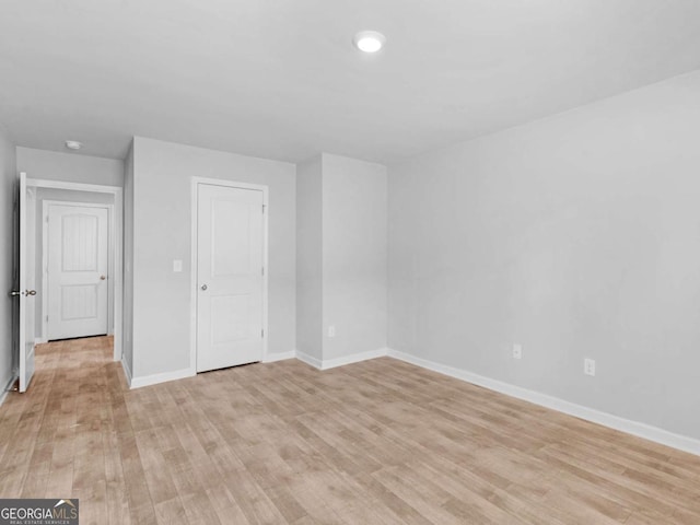 spare room featuring baseboards and light wood-style floors