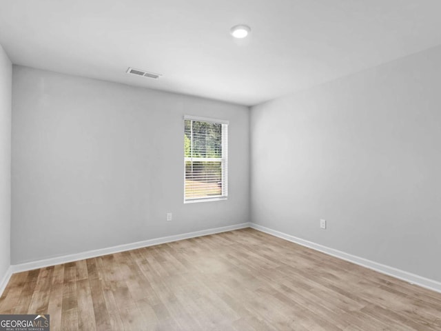 spare room featuring baseboards, light wood-type flooring, and visible vents