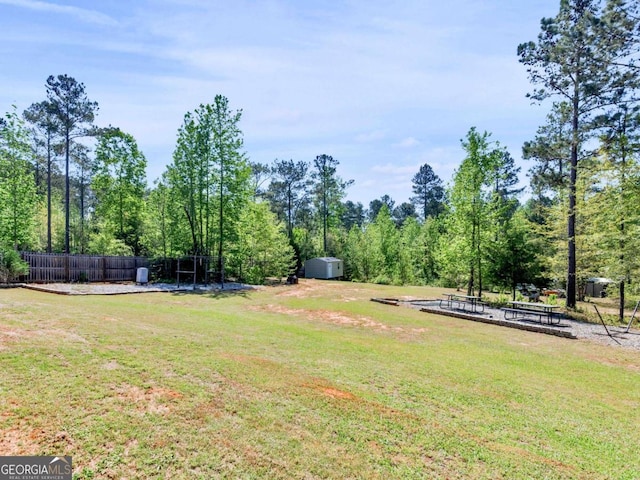view of yard with an outdoor structure, fence, and a shed