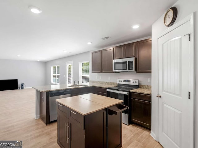 kitchen with visible vents, a peninsula, dark brown cabinets, light wood-type flooring, and stainless steel appliances