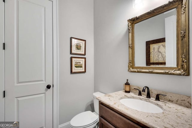 half bath featuring vanity and toilet
