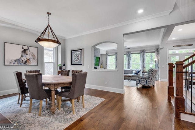 dining area featuring baseboards, dark wood finished floors, arched walkways, crown molding, and stairway