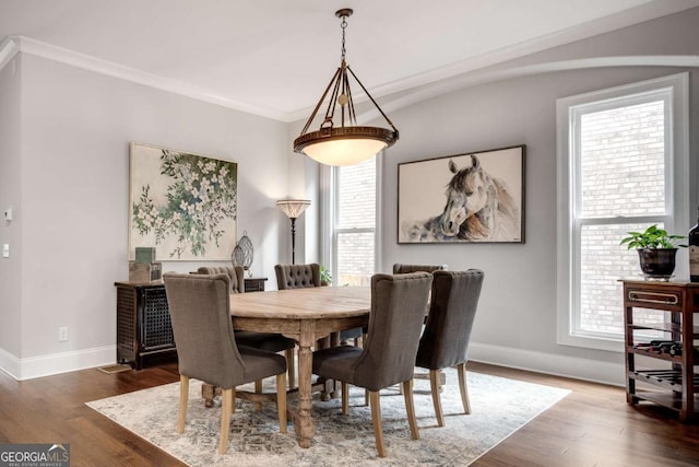 dining space with baseboards, wood finished floors, and ornamental molding