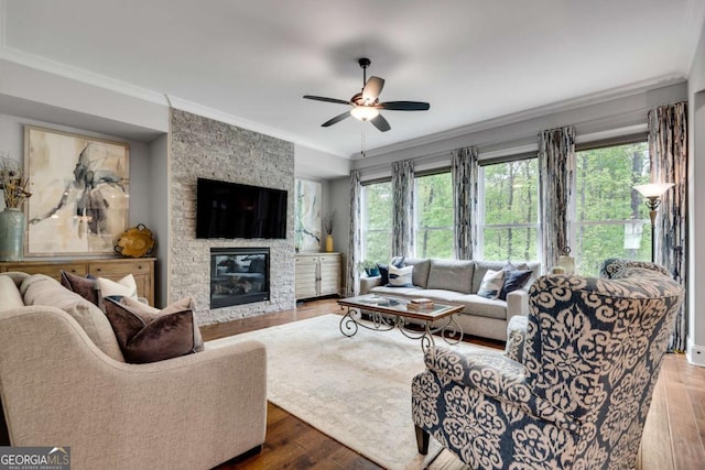 living room with crown molding, ceiling fan, hardwood / wood-style floors, and a fireplace