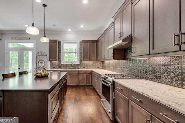 kitchen with under cabinet range hood, stainless steel appliances, a sink, dark wood-style flooring, and ornamental molding