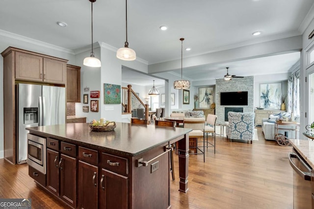 kitchen with appliances with stainless steel finishes, a ceiling fan, ornamental molding, decorative light fixtures, and dark wood-style flooring