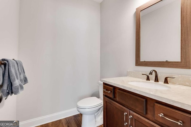 bathroom with vanity, baseboards, toilet, and wood finished floors