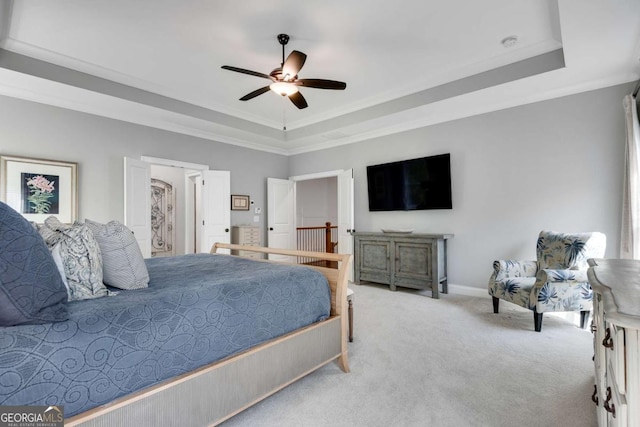 carpeted bedroom with a raised ceiling, ornamental molding, baseboards, and a ceiling fan