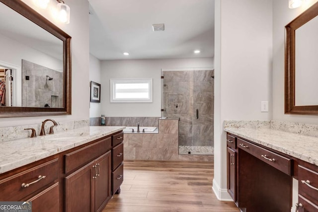 full bathroom featuring a stall shower, wood finished floors, a bath, vanity, and recessed lighting