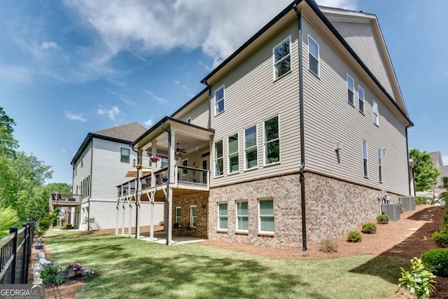 back of house featuring a ceiling fan, a lawn, a balcony, a patio, and brick siding