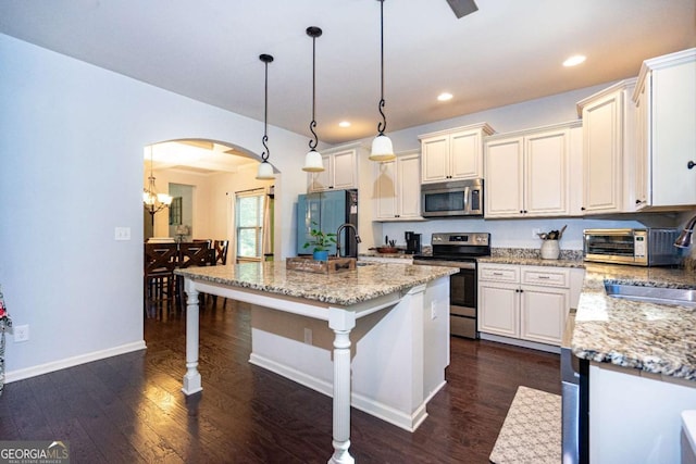kitchen with appliances with stainless steel finishes, arched walkways, a breakfast bar, recessed lighting, and dark wood-type flooring
