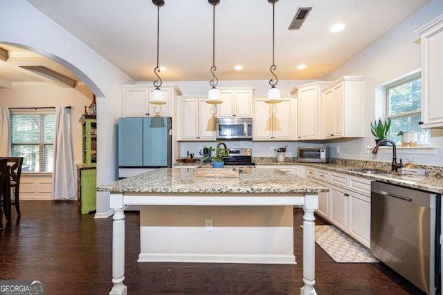 kitchen featuring visible vents, dark wood-type flooring, light stone counters, a sink, and stainless steel appliances
