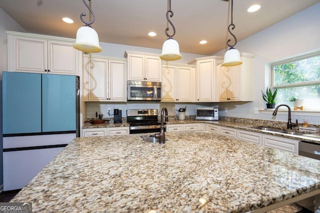 kitchen featuring pendant lighting, appliances with stainless steel finishes, a sink, light stone counters, and recessed lighting