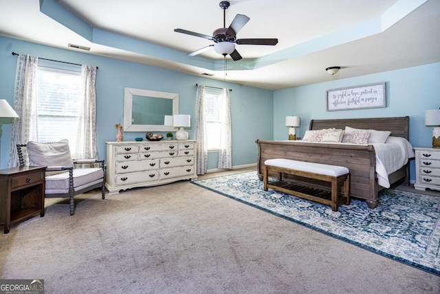 bedroom with a raised ceiling, multiple windows, carpet, and visible vents