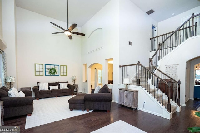 living room with wood finished floors, arched walkways, ceiling fan, and a high ceiling