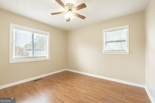 empty room featuring a ceiling fan, baseboards, visible vents, and light wood-type flooring