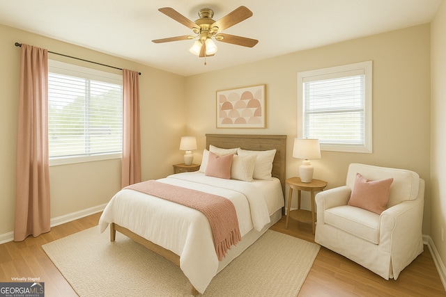 bedroom featuring light wood-style floors, baseboards, ceiling fan, and multiple windows