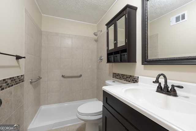 bathroom with visible vents, vanity, toilet, tiled shower, and a textured ceiling