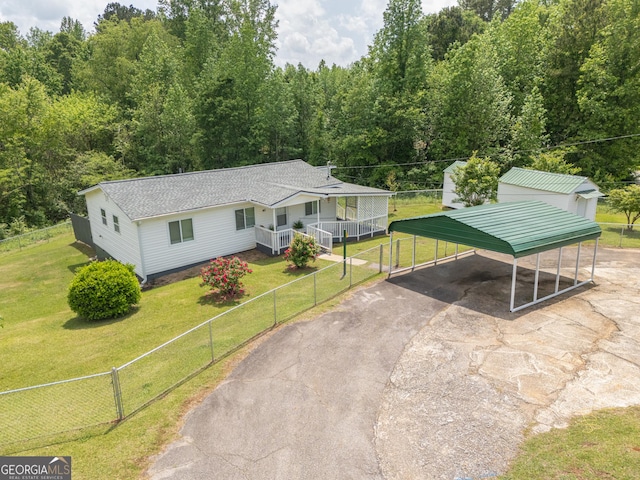 view of front of home with a detached carport, fence, driveway, and a front yard