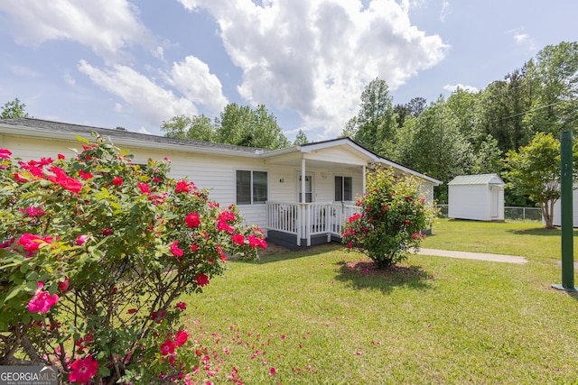rear view of property featuring fence, a storage unit, a porch, an outbuilding, and a yard