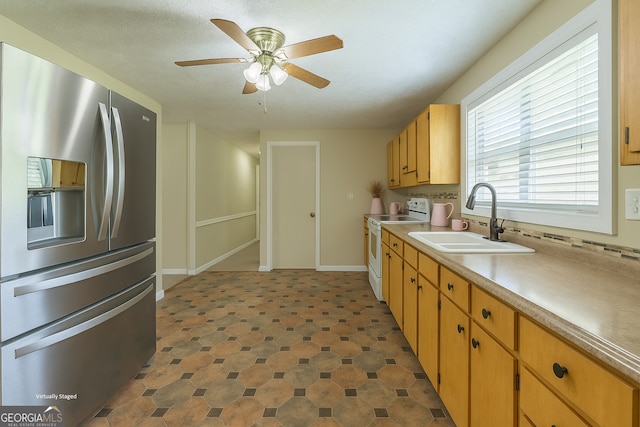 kitchen with a ceiling fan, white range with electric cooktop, light countertops, a sink, and stainless steel fridge