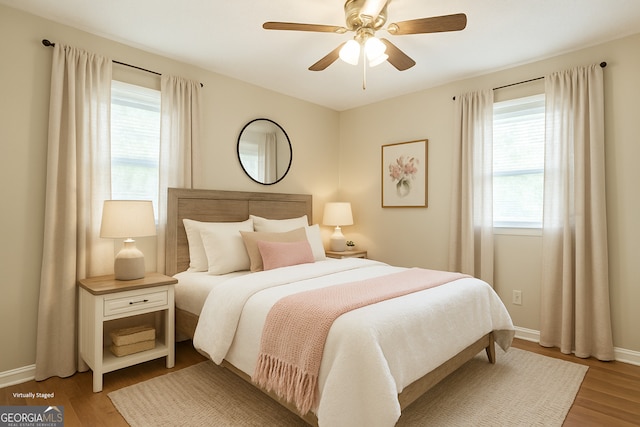bedroom featuring baseboards, multiple windows, and light wood finished floors