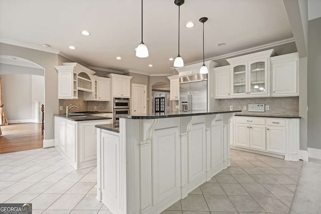 3689 Spring Hill Rd SE, Smyrna, GA 30080 - kitchen featuring arched walkways, appliances with stainless steel finishes, light tile patterned floors, and ornamental molding