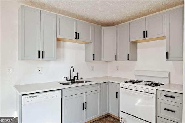 kitchen featuring white appliances, light countertops, a textured ceiling, a sink, and gray cabinetry
