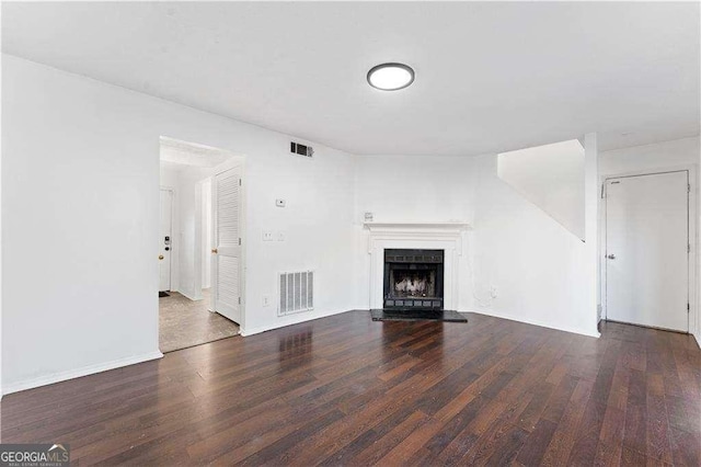 unfurnished living room featuring visible vents, baseboards, wood finished floors, and a fireplace