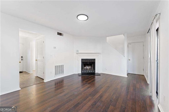 unfurnished living room featuring a fireplace with raised hearth, wood finished floors, and visible vents