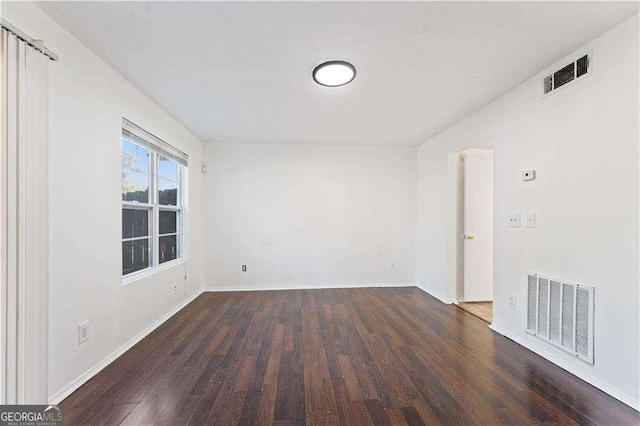 empty room with baseboards, visible vents, and wood finished floors