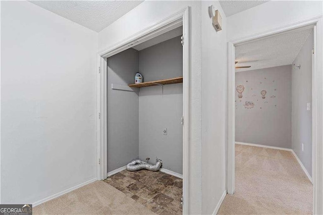 laundry room featuring baseboards, carpet, and a textured ceiling