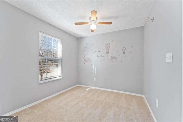 unfurnished room with baseboards, ceiling fan, a textured ceiling, and light colored carpet