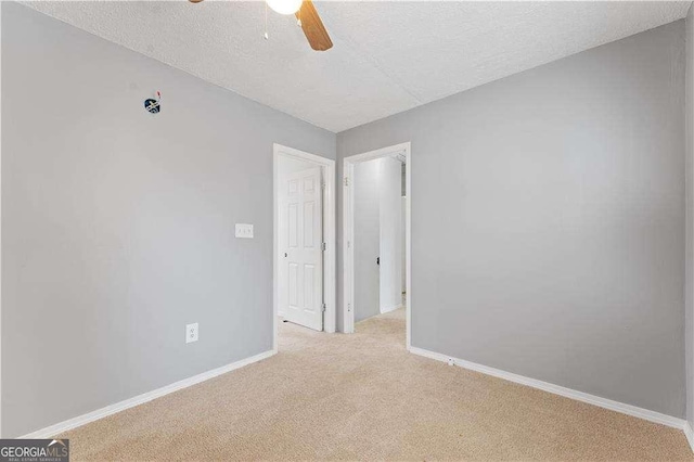 unfurnished room featuring a textured ceiling, ceiling fan, light colored carpet, and baseboards