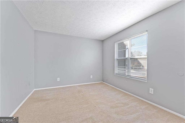 unfurnished room with carpet floors, a textured ceiling, and baseboards